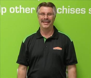 Man smiling wearing a black shirt in front of a green background