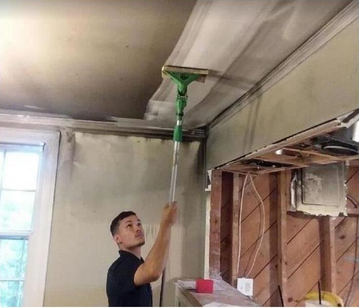SERVPRO tech cleaning smoke from ceiling