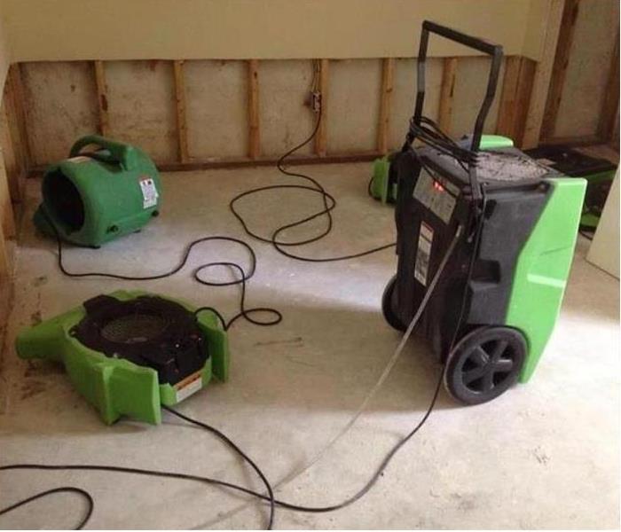 SERVPRO restoration equipment being used to dry water damage; flood cuts and drywall removed to studs