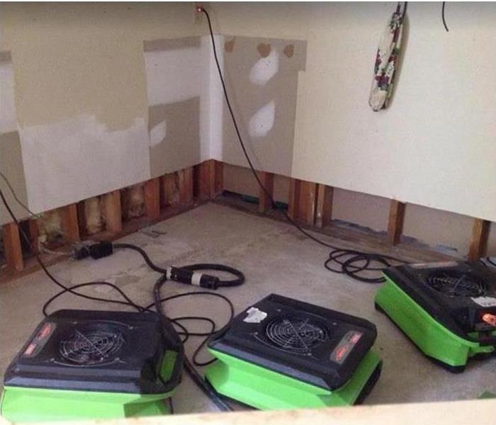 SERVPRO restoration equipment being used in water damaged room; flood cuts along walls